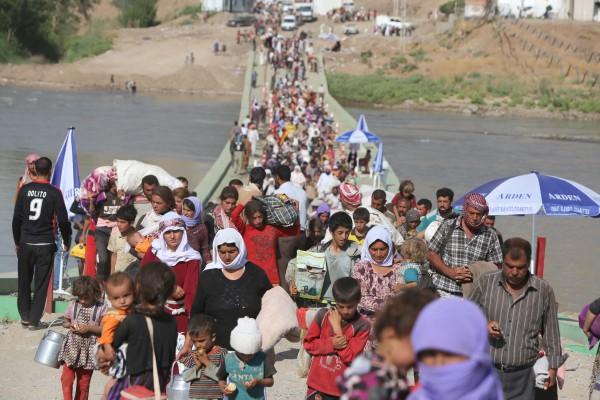 Yazidier som flytt undan extremister ur Islamiska staten (IS) korsar gränsen mellan Syrien och Irak längs bron över floden Tigris i Fishkhaburkorsningen, i norra Irak, den 13 augusti, 2014. Minst 20 000 civila, varav de flesta är från yazidifolket vilka hade blivit belägrade av jihadister på ett berg i norra Irak, har lyckats fly till Syrien och blivit eskorterade av kurdiska styrkor tillbaka in i Irak, sade tjänstemän. (Foto: Ahmad Al-Rubaye / AFP / Getty Images)
