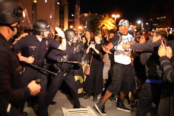 Demonstranter och polis drabbar samman framför Los Angeles polishögkvarter i Kalifornien på måndag morgon 25 november. Upplopp och demonstrationer pågick i flera städer i USA efter åtalsjuryns beslut att inte åtala en vit polis som hade skjutit ihjäl en obeväpnad svart tonåring i Ferguson, Missouri. Polisen Darren Wilson sköt 18-årige Michael Brown den 9 augusti. (Foto: David McNew / Getty Images)

