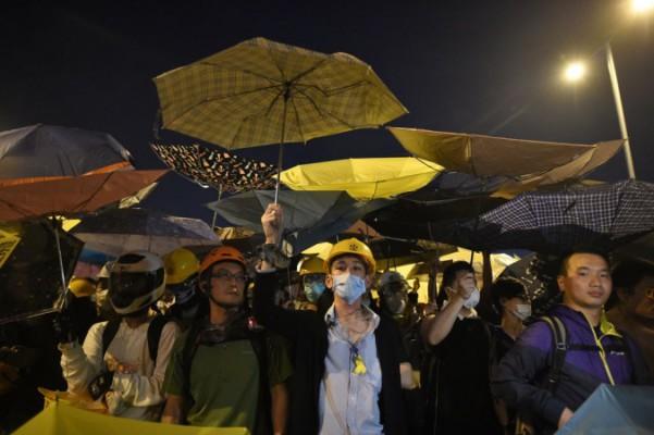 Demonstranter håller upp paraplyer, en symbol för de prodemokratiska protesterna, under en sammandrabbning med polisen under protesterna i närheten av regeringshögkvarteret i Hongkong den 30 november 2014. Demonstranterna vill ha fria val till Hongkongs högste ledare 2017, men Peking kräver att en kommitté som är lojala mot dem ska välja ut kandidaterna. (Philippe Lopez/AFP/Getty Images)