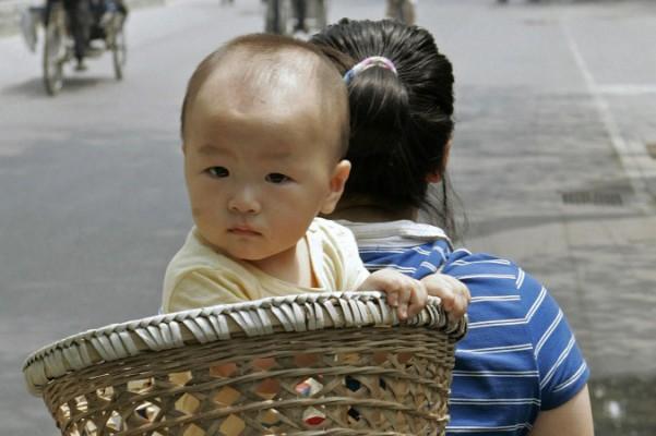 På den här arkivbilden från juni 2007 bärs ett litet barn i en korg av sin mamma på en gata i Peking. I Shandongregionen har partikadrer kommit på ett sätt att klara sina påtvingade kvoter med tvångsaborter. (Peter Parks/AFP/Getty Images)