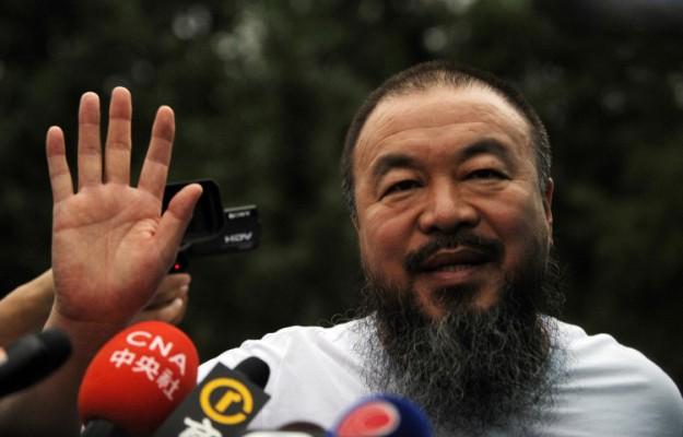 Den frispråkige konstnären Ai Weiwei vinkar till reportrar utanför sin ateljé i Peking den 23 juni. (Peter Parks/AFP/Getty Images)