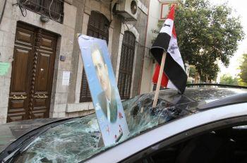 Den syriska flaggan och ett foto av president Bashir al-Assad lämnades kvar på en bil som vandaliserades av syriska lojalister utanför den franska ambassaden i Damaskus på måndagen. (Foto: Louai Beshara/AFP/Getty Images)