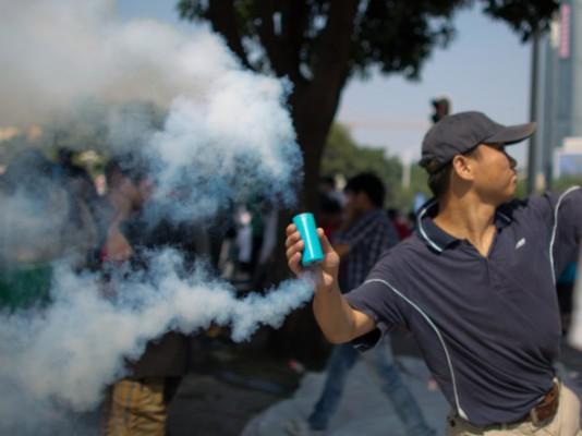 En antijapansk demonstrant kastar en gasbehållare under protester mot Japans köp av de omstridda Diaoyu/Senkaku-öarna det 16 september i Shenzhen, Kina. (Foto: Lam Yik Fei/Getty Images)
