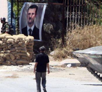 Ett foto av Syriens president Bashar al-Assad är upphängd på ett staket vid en militär kontrollstation vid infarten till staden Jisr al-Shughur i norra Syrien den 20 juni. (Foto: Louai Beshara/AFP/Getty Images)