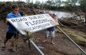 Greg Messenger till vänster och Gary Clem försöker ställa upp en varningsskylt mot översvämningar som hade dragits ned av den översvämmade floden, Burnett River, den 2 januari 2011. (Foto:Torsten Blackwood/AFP/Getty Images)