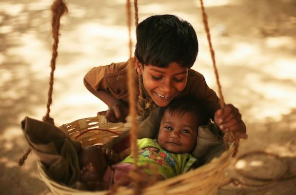 En pojke gungar sin lillasyster i en hängande korg på en marknad i Indien, 27 mars 2010. (Foto: Mark Kolbe/Getty Images)