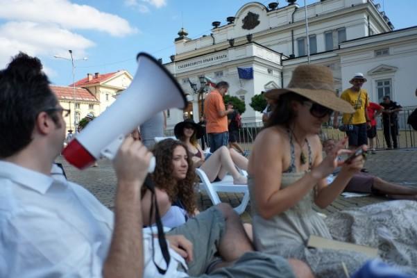 En man ropar slagord i en megafon medan strandklädda demonstranter samlas framför parlamentsbyggnaden i Sofia 31 juli 2013. Den 14 juni krävde bulgarerna avgång av vad de kallar en maffiainfluerad regering och har sedan dess gått ut på gatorna i tusental över hela landet. (Foto: Dimitar Dilkoff/AFP/Getty Images)
