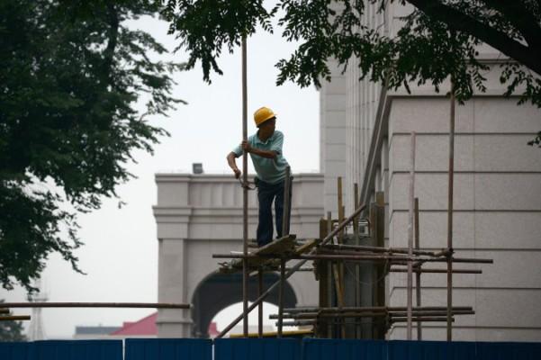 Denna bild, tagen den 11 juli 2013, visar en kinesisk arbetare som sätter upp byggnadsställningar i Peking. Den kinesiska BNP:n ser ut vara en biljon dollar mindre än man trott, enligt en ekonom som nagelfarit siffror. (Foto: Wang Zhao/AFP/Getty Images)