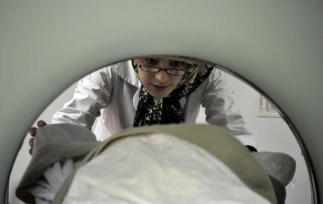 En röntgentekniker förbereder ett barn som ska genomgå en datortomografiundersökning. (Foto: Bay Ismoyo/ AFP)