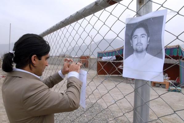 En afghansk kvinnlig journalist sätter en bild av den kidnappade Ajmal Naqshbandi mot ett staket i Kabul i mars 2007. Han kidnappades tillsammans med en italiensk journalist åt vilken han arbetade som tolk. Italienaren har släppts i utbyte mot fem talibaner medan Ajmal Naqshbandi har dödats av talibaner. (Foto: AFP/Shah Marai)