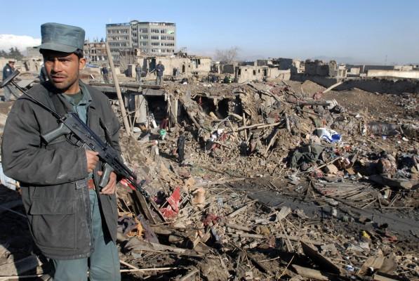 En afghansk polisman vaktar när frivilliga söker efter efterlevande i ruinerna av en affär i Kabul den 14 mars 2007. Den massiva explosionen i en affär har skakat Afghanistans kapital, Kabul, då fyra personer dödades och nio skadades, sade polisen. Bomben detonerade i en basar där man säljer vaktvapen, krut och ammunition. (Foto: AFP/ Shah Marai)