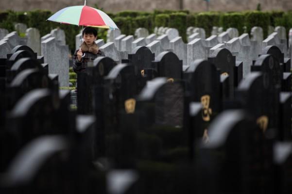 En pojke står mellan gravar under den årliga Qingmingfestivalen, eller ”gravsopningsdagen” på en offentlig begravningsplats i Shanghai, 6 april 2015. (Johannes Eisele/AFP/Getty Images)