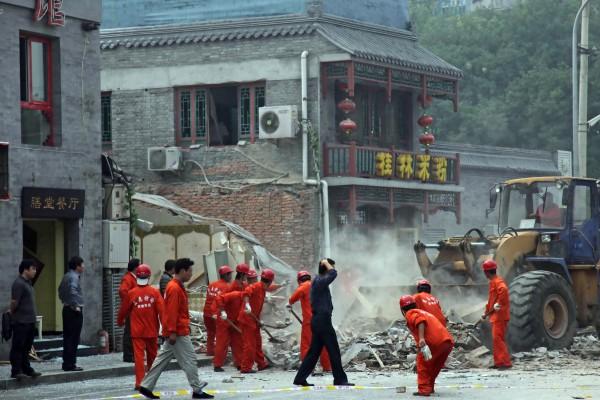 Kinesisk polis och säkerhetspersonal vaktar medan arbetare städar upp efter en explosion som förstörde en restaurang i centrala Peking. (Foto: AFP)

