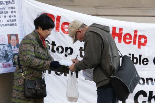 En förbipasserande i Sydney, Australien, undertecknar en petition som uppmanar till ett slut på organstölder från levande Falun Gong-utövare i Kina, den 6 juli 2013. Underskriften är en av nära 1,5 miljoner från hela världen som överlämnades till kontoret för FN:s  för mänskliga rättigheter den 9 december 2013. (Foto: Minghui.org)