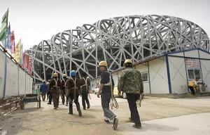 Arbetare på väg till Pekings olympiastadion, känd som "Fågelboet" i Peking. Den tyska firman Covertex, en entreprenör som utför takarbeten på olympiastadion, har nyligen ansökt om konkurs. (Foto: Peter Parks/AFP/Getty Images)