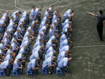 Fångar lyssnar på en polis under skolning i uppträdande i ett fängelse i Chongqing den 30 maj 2005. (Foto: China Photos/Getty Images)