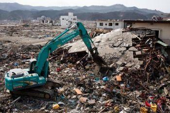 Japanska arbetare använder en hydraulisk maskin för att riva en förstörd byggnad i den tsunamidrabbade staden Rikuzentakata den 2 april. (Foto: Yasuyoshi Chiba/AFP/Getty Images)