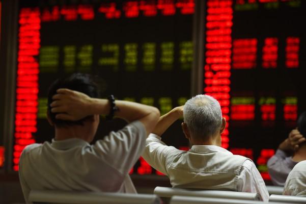 Kinesiska investerare tittar på skärmar som visar aktiemarknadens kurser på ett värdepappersbolag i Peking den 14 juli, 2015. Myndigheterna  har suspenderat hundratals företag från aktiemarknaden de senaste veckorna för att förhindra en marknadshärdsmälta, efter att Shanghai index hade fallit med 30 procent på tre veckor. Miljarder dollar försvann i börsvärde, och spred smitta på regionala marknader och väckte en skräck över den potentiella effekten på den reala ekonomin. (Foto: Greg Baker /AFP /Getty Images)
