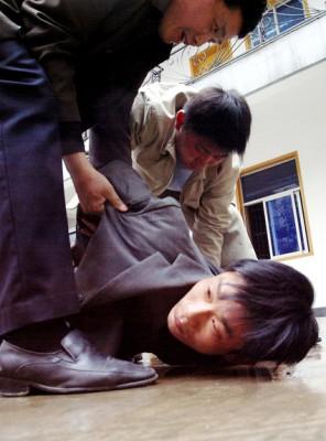 Civilklädda kinesiska poliser griper en snattare.  En provins i södra Kina har utökat landets utbredda användning av dödstraff till att även gälla snattare, i ett försök att hämma en våg av väskryckande motorcyklister. (Foto: AFP)