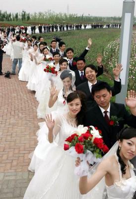 Över 100 par gifte sig samtidigt i en park i Shenyang i Liaoningprovinsen. I dagens Kina har giftermål blivit något mer än själva ceremonins innebörd och betydelse. Utgifterna kan vara tusentals gånger högre än för deras föräldrars generation, för 25 år sedan.  Motsvarande 200 000 SEK läggs utan vidare ut, vilket kan vara föräldragenerationens hela livsbesparing. (Foto: CHINA OUT AFP PHOTO)