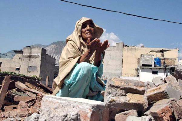 En överlevande från jordbävningen i Kashmir 2005 ber en bön sittandes på kvarlevorna av sitt hem i Muzaffarabad. (Foto: AFP/Sajjad Qayyum)