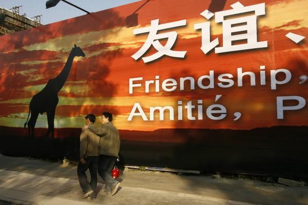 Två byggarbetare i Peking passerar en av många gigantiska propagandaskyltar för samarbetet mellan Afrika och Kina. (Foto: AFP/Peter Parks)
