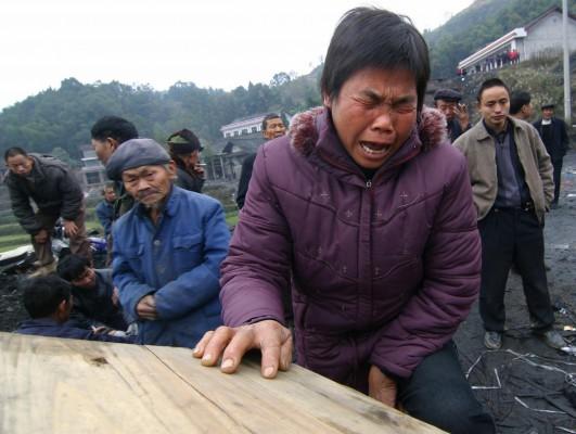 KINA, LOUDI: En kvinna sörjer, vid en död kolgruvearbetares likkista i Hunanprovinsen den 5 December 2006. Kinas kolgruvor är de farligaste i världen, nära 6.000 dödades inom landets industri förra året -- det blir en dödlighet på cirka 16 personer varje dag enligt officiella siffror. Fackrörelser menar dock att det verkliga antalet kan vara så högt som 20.000 per år. De menar att statsanställda och gruvägare ofta mörklägger olyckor. (Foto: AFP / STR)