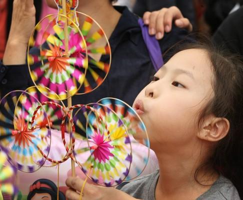 Förberedelserna inför nyårfester pågår över hela världen. En flicka blåser på en papperssnurra i Hongkong, 16 februari 2007. (Foto: AFP / Mike Clarke)
