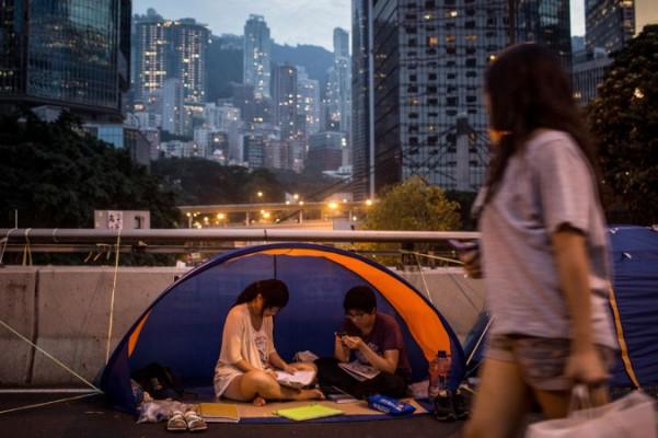 Demokratiaktivister läser i ett tält på en gata utanför Hongkongs regeringskomplex den 26 oktober 2014 i stadsdelen Admiralty i Hongkong. En medlem av rörelsen Scholarism stoppades nyligen av tullen när han försökte resa till staden Shenzhen, som ligger precis vid Hongkong, fast på fastlandet den 7 november 2014. (Foto: Chris McGrath/Getty Images)