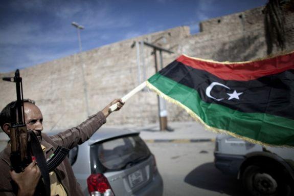 En libysk stridskämpe viftar med nationella övergångsrådets (NTC) flagga när han firar på gatorna i Tripoli efter nyheten om Muammar Gaddafis tillfångatagande den 20 oktober. (Foto: Marco Longari/AFP/Getty Images)
