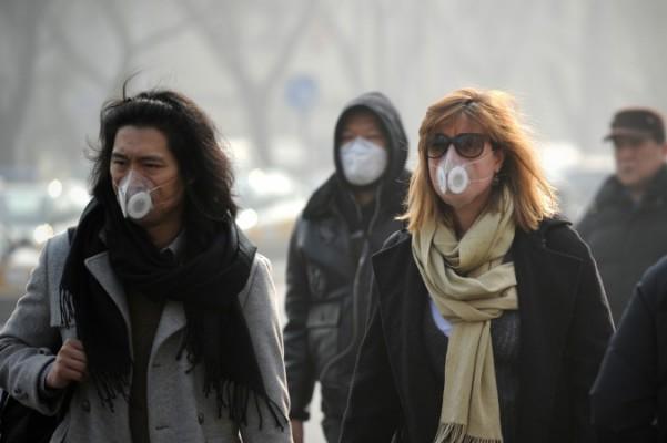 Folk som bär andningsmasker promenerar på en gata i Peking den 16 januari 2014. Kinesiska vetenskapsmän har hittat 1 315 typer av inandningsbara mikroorganismer i den förorenade luften i landets huvudstad. (Wang Zhao/AFP/Getty Images)