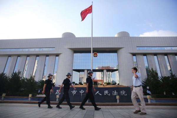 Poliser patrullerar vid porten till Kunmings Intermediate Court i Kunming, Yunnanprovinsen i sydvästra Kina den12 september 2014. Foto: STR/AFP/Getty Images