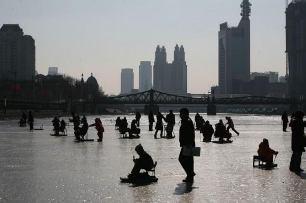 På bilden syns folk på den frusna Haihefloden den 26 januari 2009 i Tanjin, Kina. (China Photos/Getty Images)