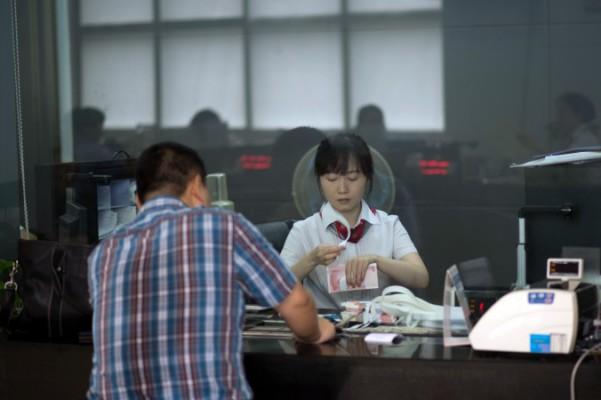 En bankanställd betjänar en kund i Shanghai den 24 september 2014. (Foto: Johannes Eisele/AFP/Getty Images)