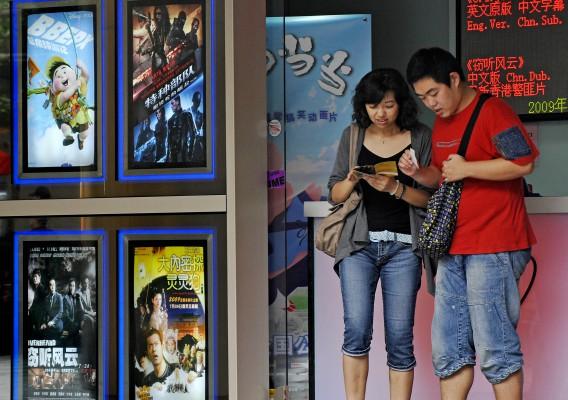 Ett kinesiskt par kontrollerar sina biobiljetter i Shanghai, Kina den 17 augusti. (Foto: Philippe Lopez/ AFP)