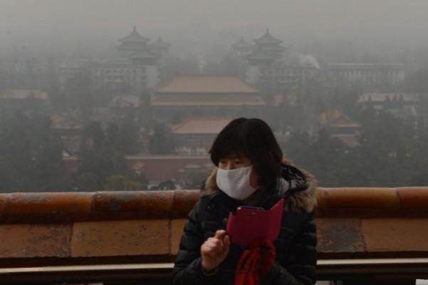 En kinesisk turist fotograferar i den historiska Jingshanparken medan smogen breder ut sig över Peking. (Foto: Mark Ralston/AFP/Getty Images)