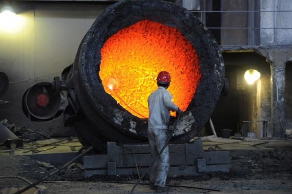 En arbetare jobbar vid en jättelik gryta i ett stålverk i Hefei i Anhuiprovinsen den 25 juni 2011. Överkapacitet inom stålindustrin och inom andra industrier är en av de stora utmaningarna i den kinesiska ekonomin 2014. (Foto: STR/AFP/Getty Images)