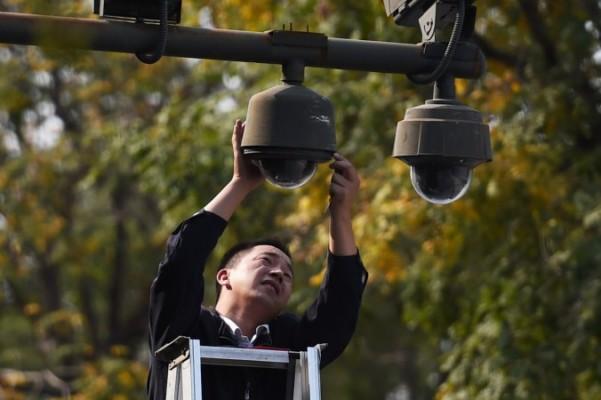 En arbetare justerar säkerhetskameror i utkanten av Himmelska fridens torg i Peking, 30 september 2014. Under nationaldagsfirandet säger sig nu polisen i Peking täcka "100 procent av huvudstaden" med sina kameror. Foto: Greg Baker /AFP/Getty Images)