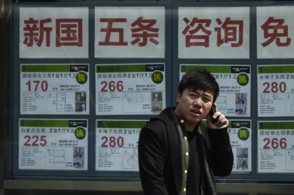 En kinesisk man pratar i sin mobiltelefon utanför en fastighetsförmedling i Peking den 15 april 2013. Ett nyligen skapat index, "bostadsköparnas eländesindex" visat hur dyrt det är att skaffa en bostad i Kina. (Wang Zhao/AFP/Getty Images)
