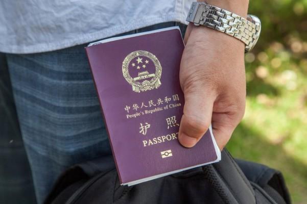 En kinesisk medborgare håller sitt pass i handen. Pekings kommunala organisationsdepartement införde nyligen en ny regel som innebär att tjänstemän måste lämna in sina pass och ansöka om att få resa utomlands enligt en strikt procedur. (Foto: Omar Havana/Getty Images)
