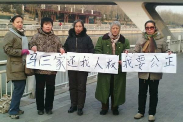 En grupp med offer för Masanjias kvinnoarbetsläger reste till Peking den 16 december och höll upp en banderoll med texten: "Masanjia, ge mig tillbaka mina mänskliga rättigheter, jag vill ha rättvisa." Enligt Human Rights Campaign in China så är Hao Wei en av personerna på bilden. (Foto: Human Rights Campaign in China)