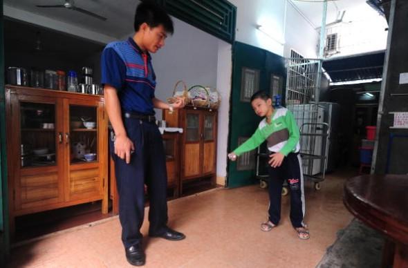 Huang Xiangyi hjälper sin sjuårige son Huang Zhouxiang, som har en CP-skada, att gå den 26 oktober 2009. (Foto: Frederic J. Brown/AFP/Getty Images)