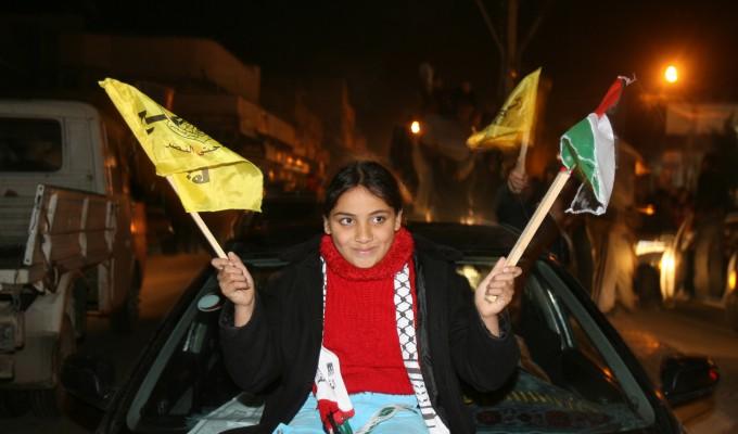 Ett avtal om en palestinsk samlingsregering är klart. I firandet på gatorna efter mötet viftar en flicka med flaggor. Fathas flagga (V) (Foto: AFP/Mahmud Hams)