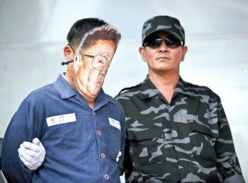 En man (vä) som låtsas vara den nordkoreansle ledaren Kim Jong Il leds till fram till en exekutionspluton under ett scenframträdande den 29 september i Seoul, när nordkoreanska soldater som hoppat av till Sydkorea bildade gruppen som ska leda en kampanj med syftet att störta kommunistregimen. (Foto: Park Ji-Hwan/AFP/Getty Images)
