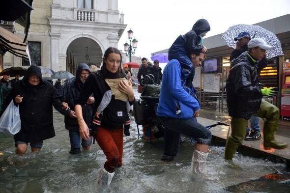 Människor vadar på en översvämmad gata i Venedig den 11 november 2012. Världsbanken har varnat för att fler översvämningar, torka, värmeböljor och andra klimatkatastrofer kan inträffa under nästa århundrade om ingen drastisk åtgärd vidtas (Foto: Marco Sabadin/AFP/Getty Images)
