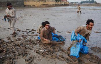 Drabbade av översvämningarna i Pakistan skyndar sig att samla in vattenflaskor som släppts ned som nödhjälp av en helikopter från det pakistanska flygvapnet den 2 augusti 2010. (Foto: Daniel Berehulak/Getty Images)