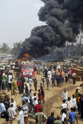 NIGERIA, Lagos: Åskådade och tjänstemän från Röda Korset tittar på brandbekämpare som försöker släcka branden efter explosionen av en oljeledning på Abule Egba i Lagos. (Foto: AFP/Pius Utomi Ekpei)
