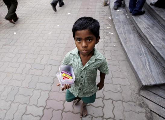 Ett indiskt barn säljer godis utanför ett handelscentrum i Kolkata i Indien. Trots att det finns förbud mot barnarbete måste många barn fortfarande arbeta för att hjälpa till med ekonomin i familjen. (Foto: AFP/Deshakalyan Chowdhury) 
