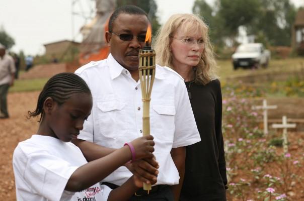 Den amerikanska skådespelerskan Mia Farrow går tillsammans med överlevande med den brinnande facklan vid en massgrav i Kigali. (Foto: AFP/Stringer/Andrew McGregor)