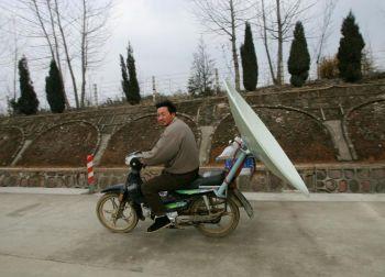 En kinesisk man som fraktar en satellitantenn på sin motorcykel i Anhuiprovinsen i Kina. (Foto: Cancan Chu/Getty Images)